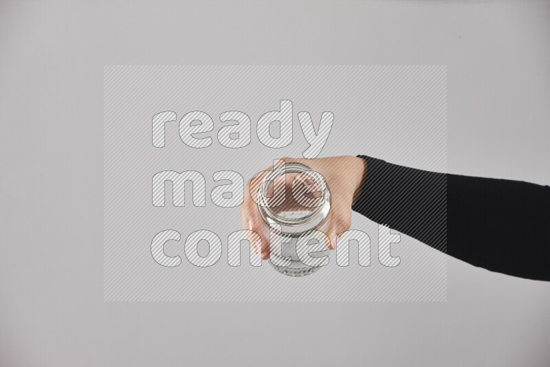 A woman in black abaya holding different glassware in different positions