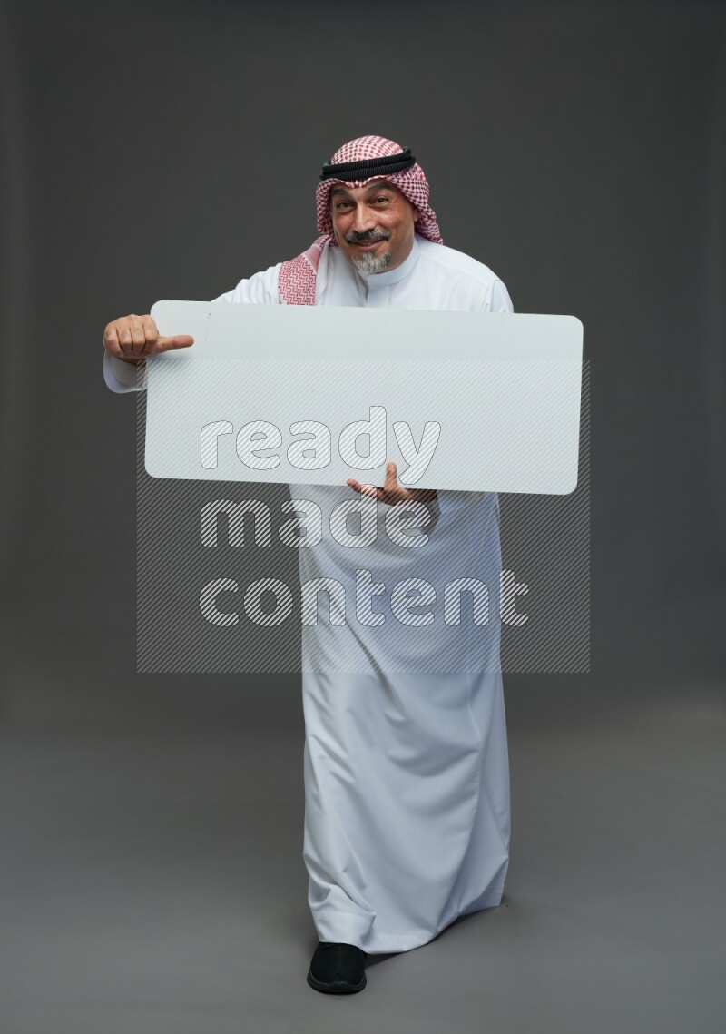 Saudi man with shomag Standing holding social media sing on gray background