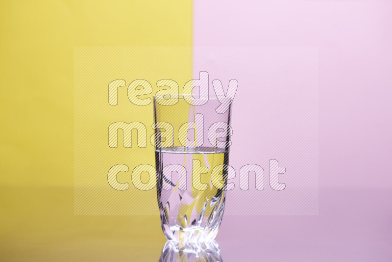 The image features a clear glassware filled with water, set against yellow and rose background