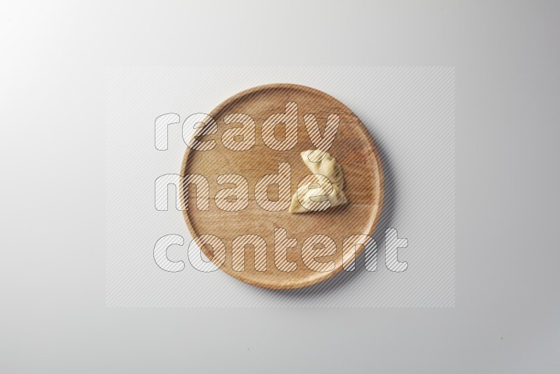 Two Sambosas on a wooden round plate on a white background