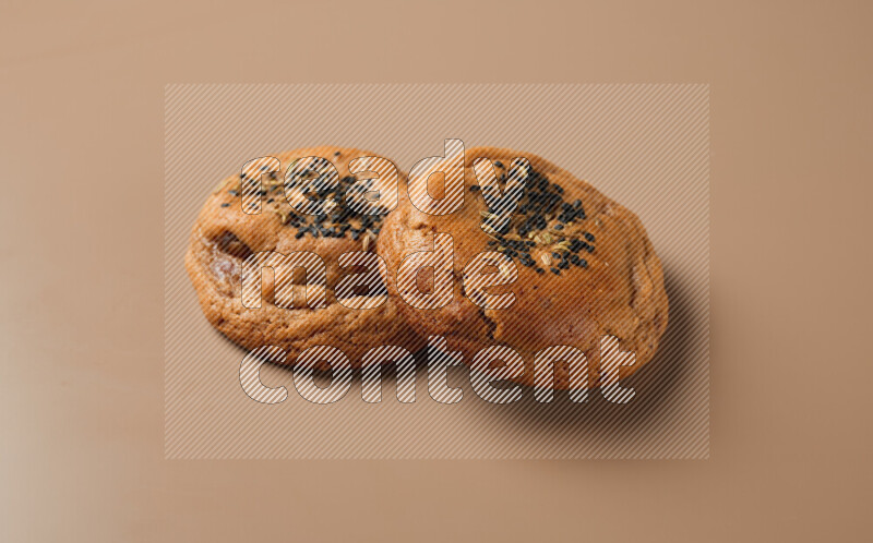 Two chocolate chip cookies on a brown background
