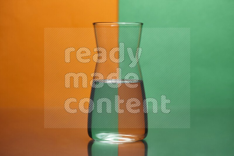 The image features a clear glassware filled with water, set against orange and green background