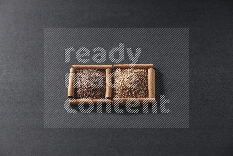 2 squares of cinnamon sticks full of mustard seeds and flaxseeds on black flooring