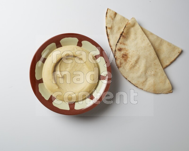Plain hummus in a traditional plate on a white background