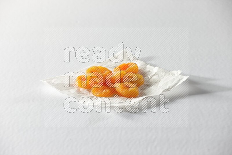 Dried apricots on a crumpled piece of paper on a white background in different angles