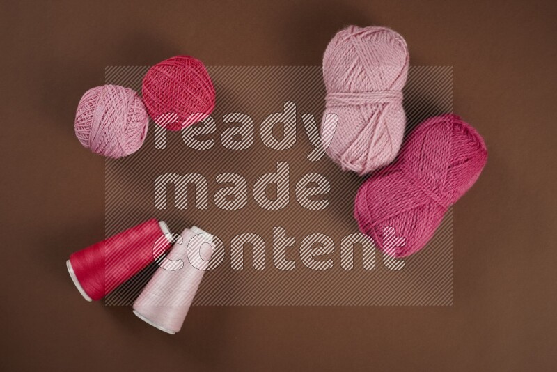 مجموعة من أدوات الخياطة والتفصيل زهرية اللون على خلفية بنية