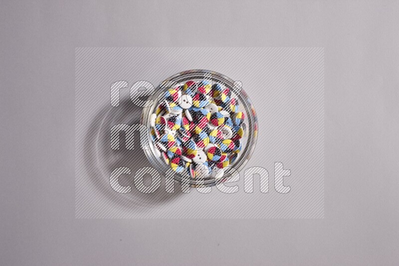 Colored buttons in a glass bowl on grey background