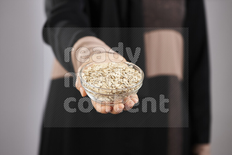 Woman in abaya holding different kinds of legumes in different positions