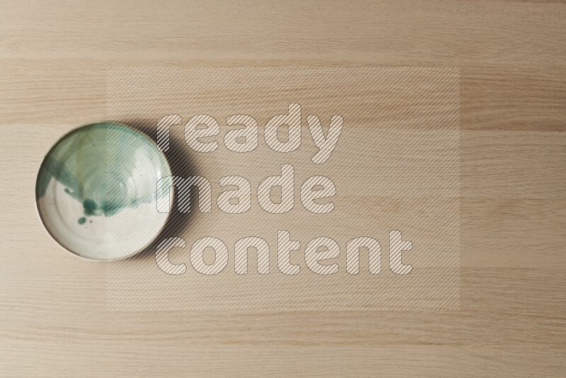 A multicolored pottery plate on light wooden background