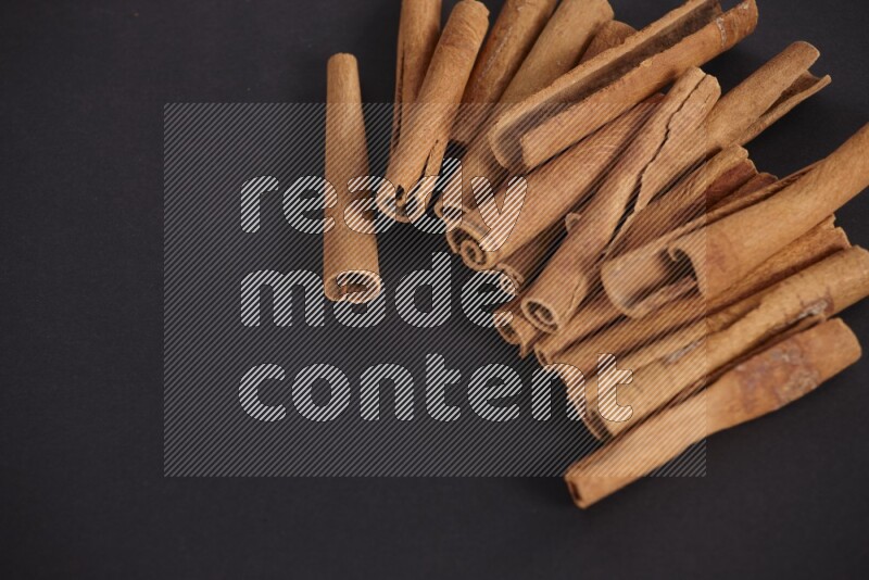 Cinnamon sticks stacked on black flooring