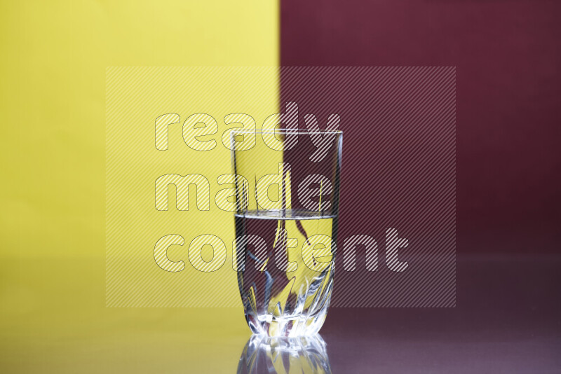 The image features a clear glassware filled with water, set against yellow and dark red background