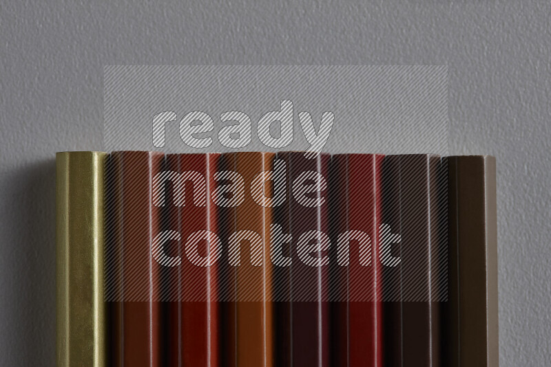 A collection of colored pencils arranged showcasing a gradient of brown hues on grey background