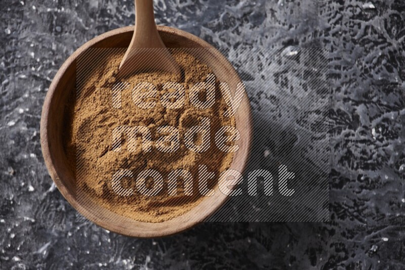 Wooden bowl full of cinnamon powder with a wooden spoon on a textured black background in different angles