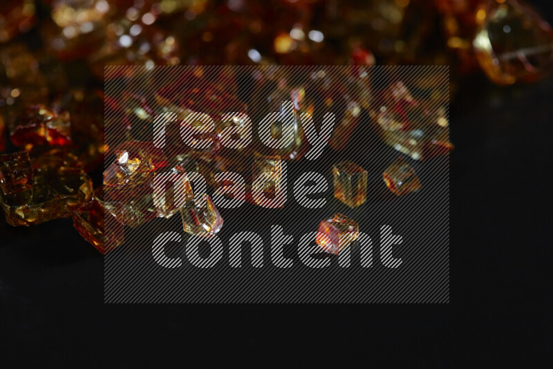 Transparent orange fragments of glass scattered on a black background