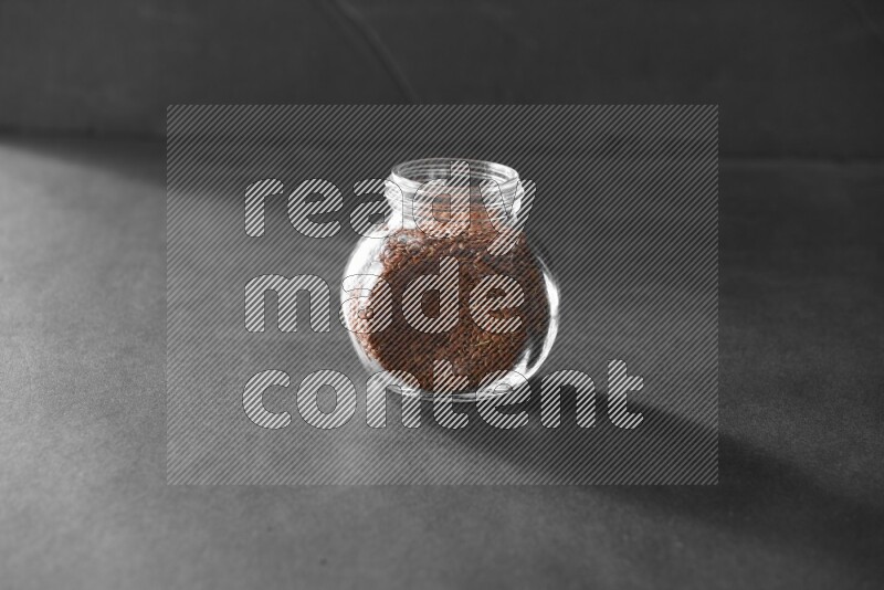 A glass spice jar full of flax on black flooring