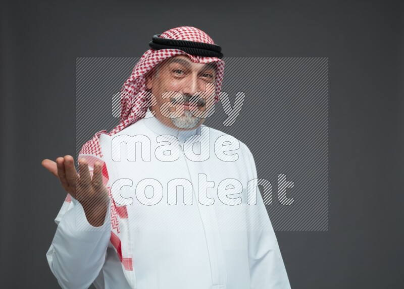 Saudi man with shomag Standing Interacting with the camera on gray background