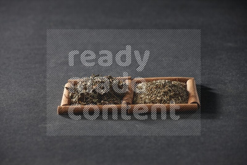 2 squares of cinnamon sticks full of cumin and dried basil on black flooring