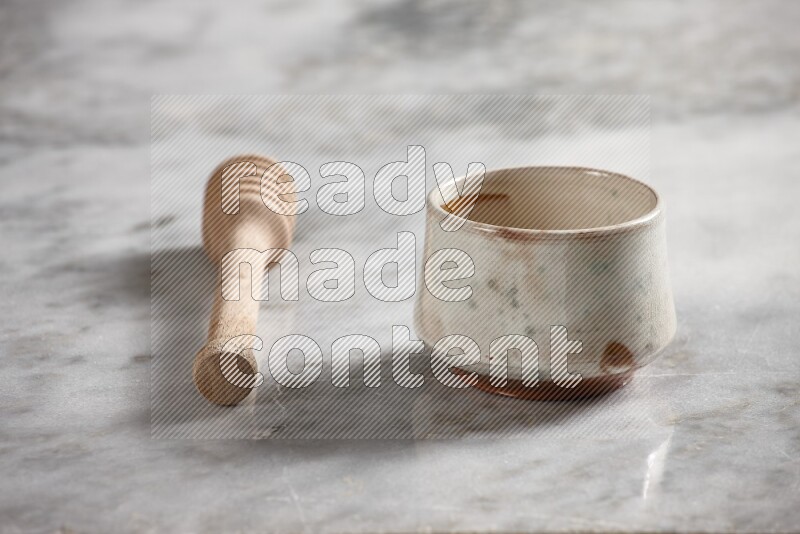 Multicolored pottery bowl with wooden honey dipper on the side on grey marble background