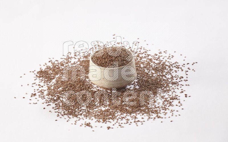 A pottery beige bowl full of flax seeds and more seeds spread on a white flooring