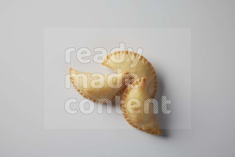 Three fried sambosa from a top angle on a white background