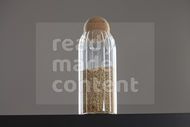 Hulled wheat in a glass jar on black background