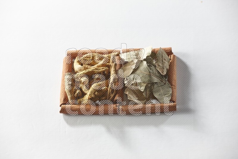 2 squares of cinnamon sticks full of turmeric fingers and bay laurel leaves on white flooring
