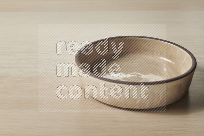 A beige pottery oven plate on light wooden background