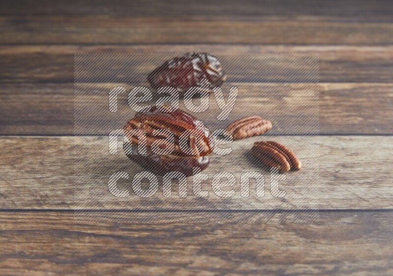 two pecan stuffed madjoul date on a wooden background