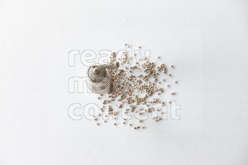 White pepper beads with a metal grinder on white flooring