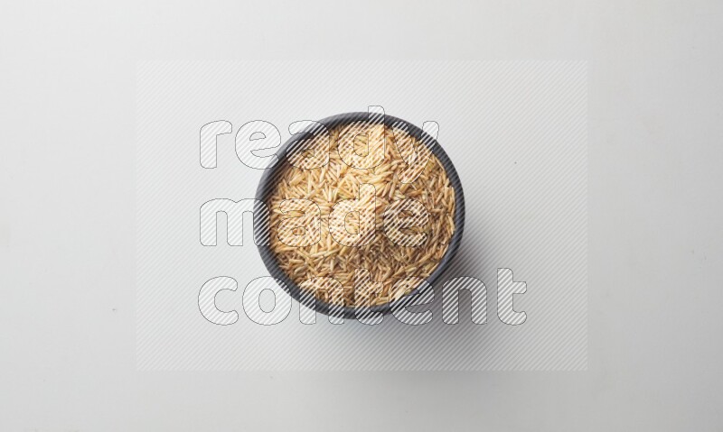 Top-view shot of long grain brown rice in a container on white background