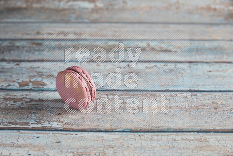 45º Shot of Purple Strawberry macaron on light blue wooden background