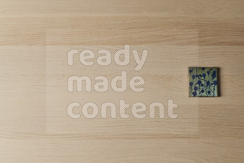 A decorative pottery coaster on light wooden background