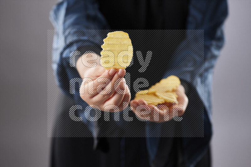 Woman in abaya holding different kinds of snacks in different positions
