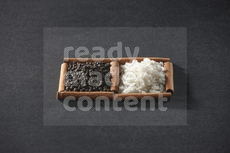 2 squares of cinnamon sticks full of white salt and black peppers on black flooring