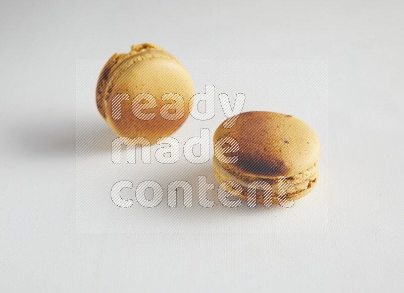 45º Shot of two Yellow Crème Brulée macarons on white background