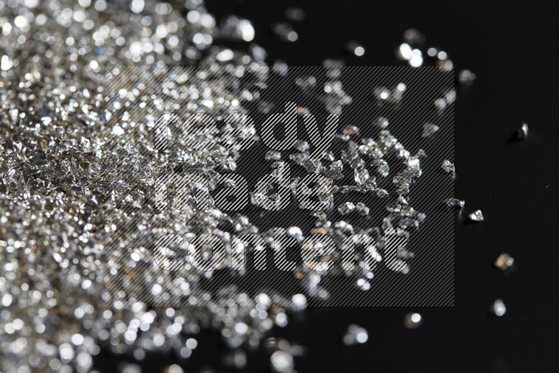 Silver shimmering fragments of glass scattered on a black background