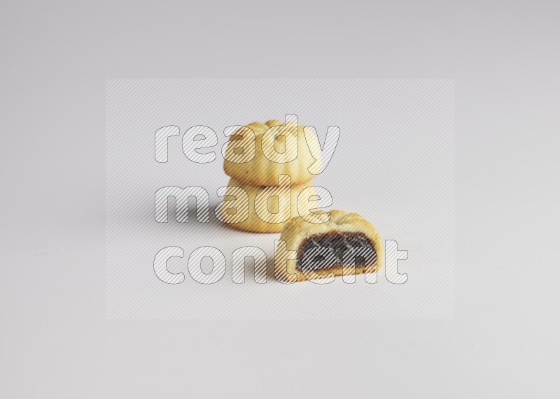 Three Pieces of Maamoul filled with date one of them is cut direct on white background