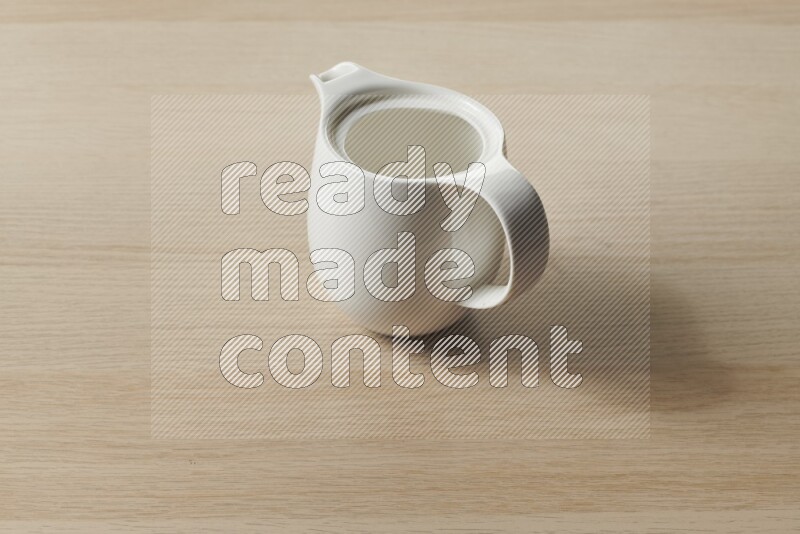 A ceramic milk jug on light wooden background