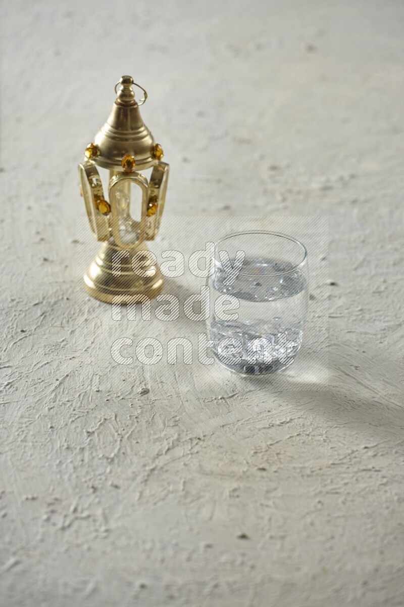 A golden lantern with different drinks, dates, nuts, prayer beads and quran on textured white background