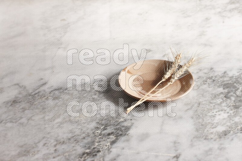 Wheat stalks on multicolored pottery plate on grey marble background