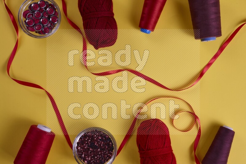 A red collection of sewing and tailoring tools arranged on a yellow background