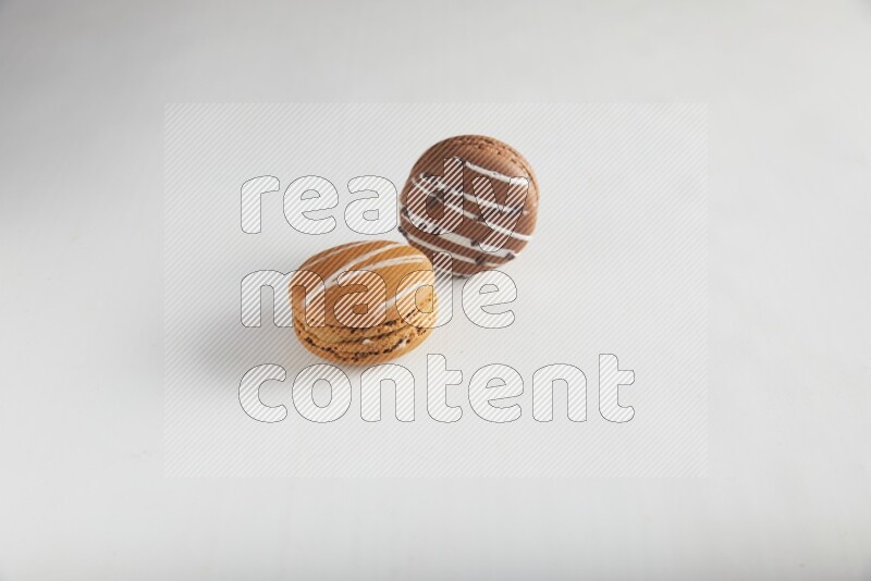 45º Shot of of two assorted Brown Irish Cream, and Brown white Chocolate Caramel macarons on white background