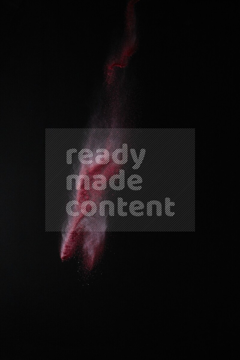 A side view of red powder explosion on black background