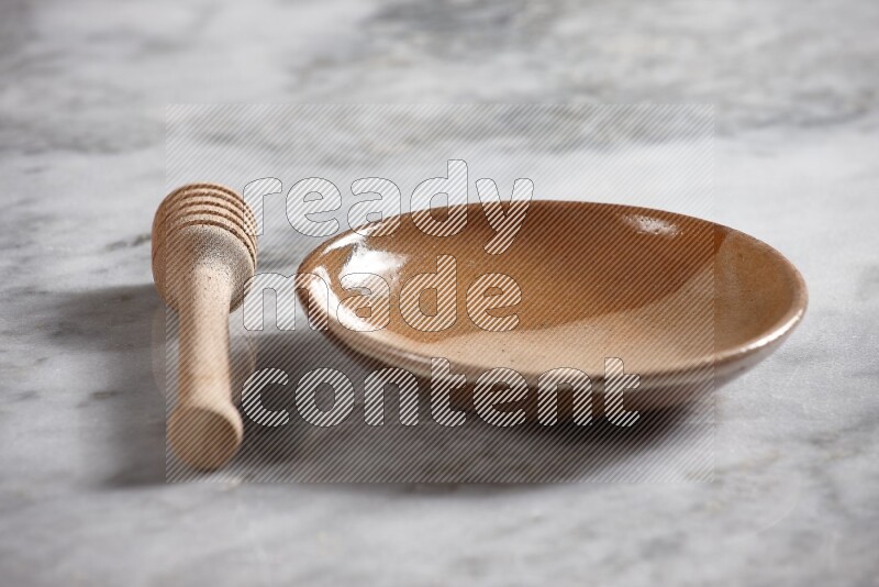 Multicolored pottery plate with wooden honey dipper on the side on grey marble background