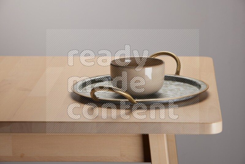 multicolored bowl placed on a rounded stainless steel tray with golden handels on the edge of wooden table