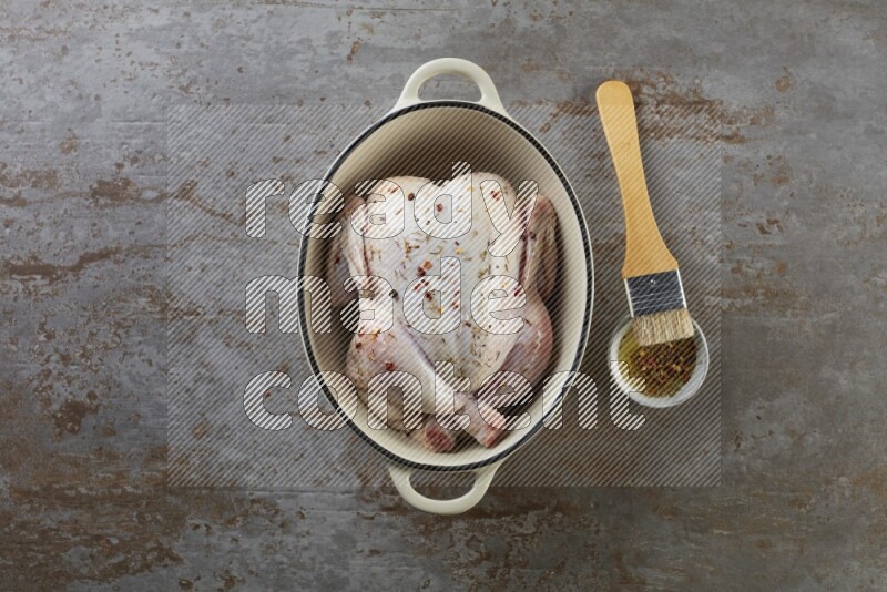 whole raw chicken on in a white ceramic pot direct on a rustic grey background