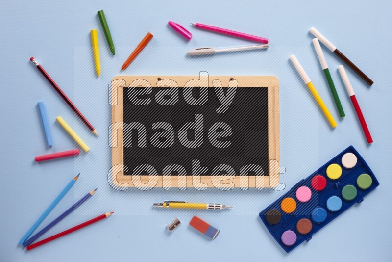 A blackboard with assorted school supplies on blue background