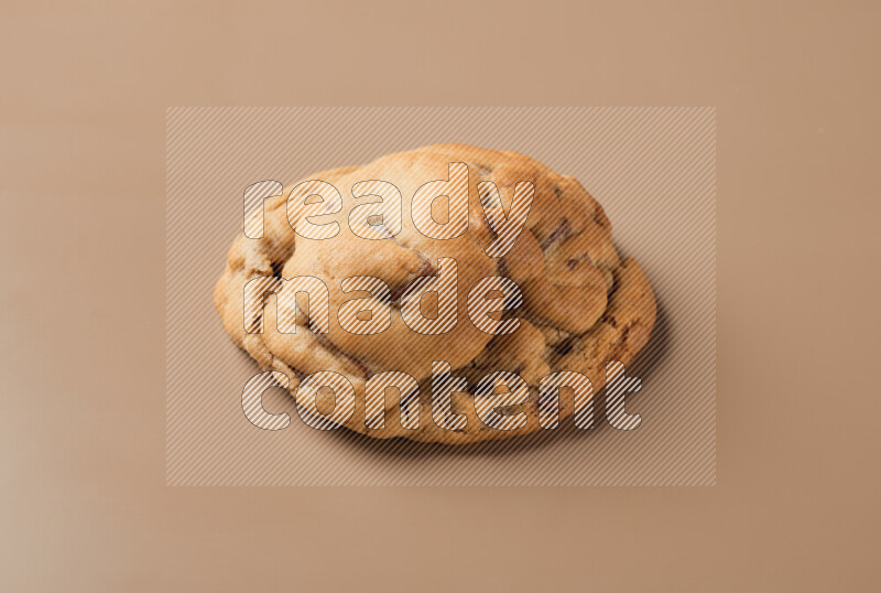 a whole chocolate chip cookie on a brown background