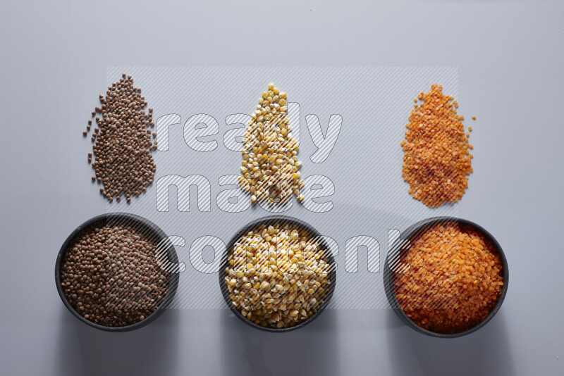 Legumes in pottery bowls on light grey background