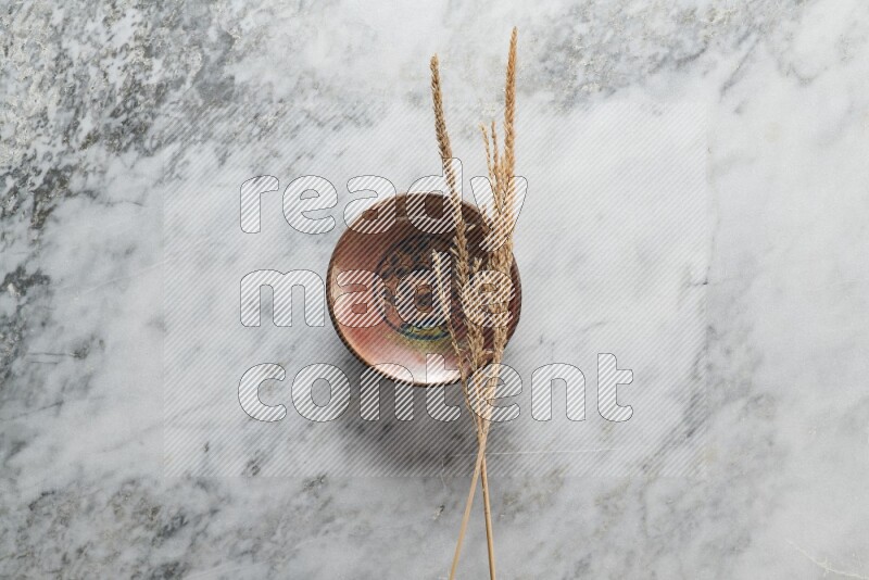Wheat stalks on decorative pottery plate on grey marble background